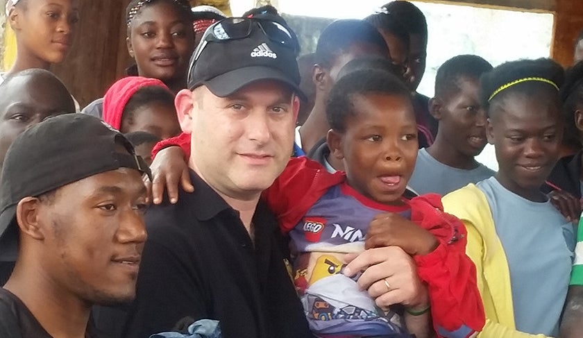 Shawn Brown holds a little boy and stands with others in a group photo