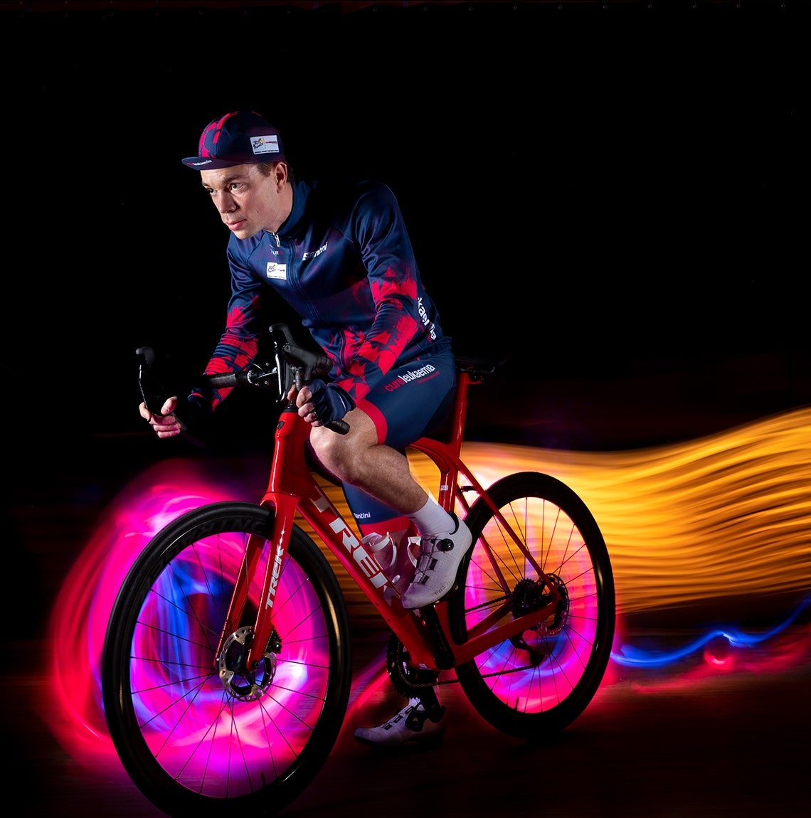 A photo illustration of neon lights surrounding Ian MacFawn riding his bike
