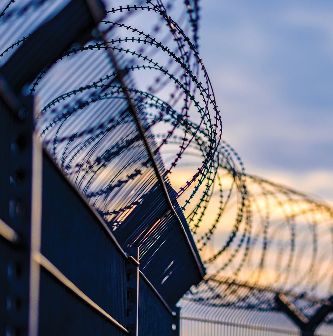 barbed curled wire fence and cloudy sky