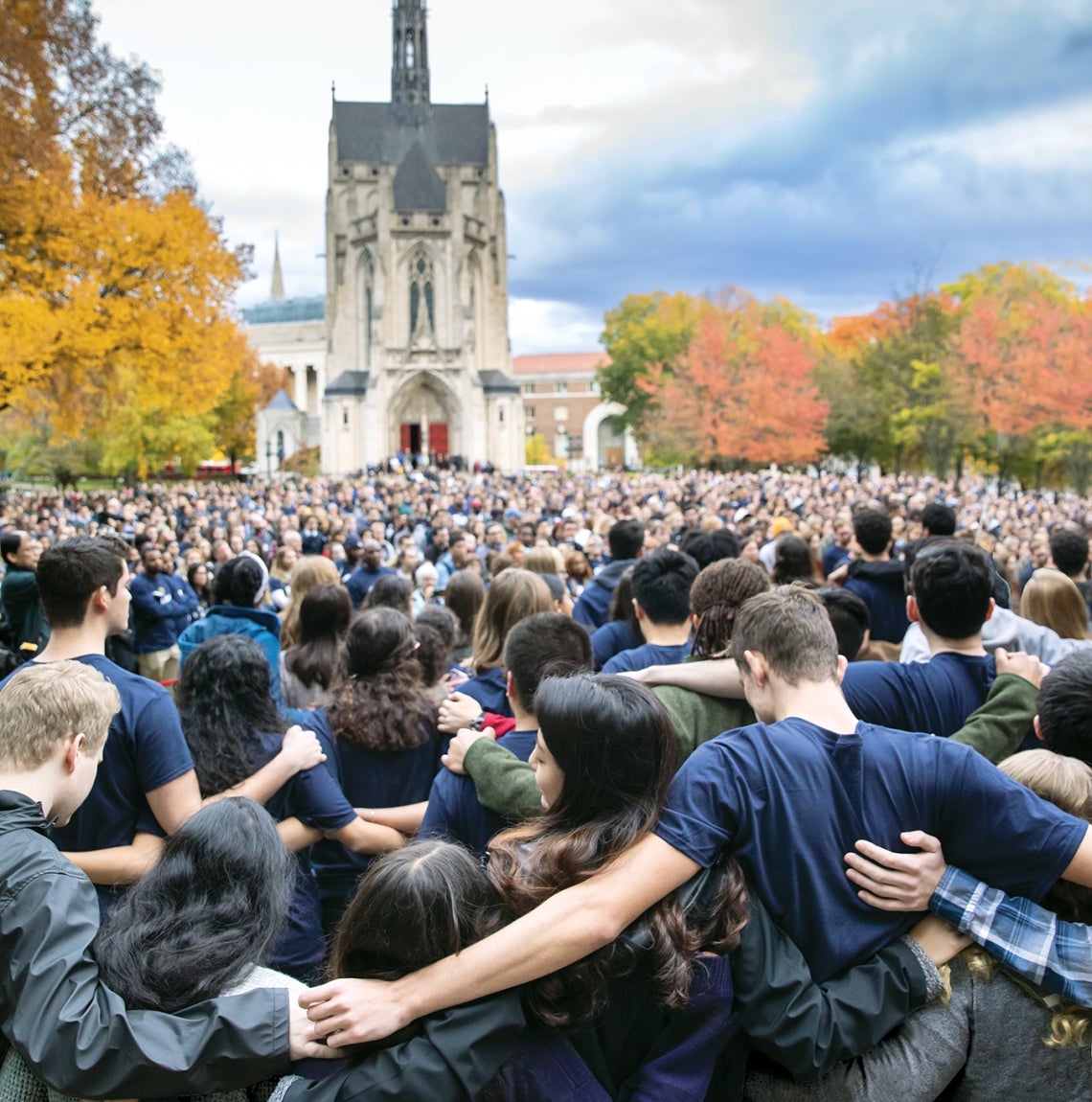 Pitt community members stand on Cathedral lawn and put arms around each other's shoulders.