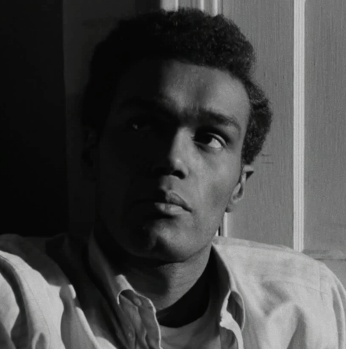 screen still of Duane Jones as Ben in "Night of the Living Dead." He is leaning back, and half of his face is in shadow