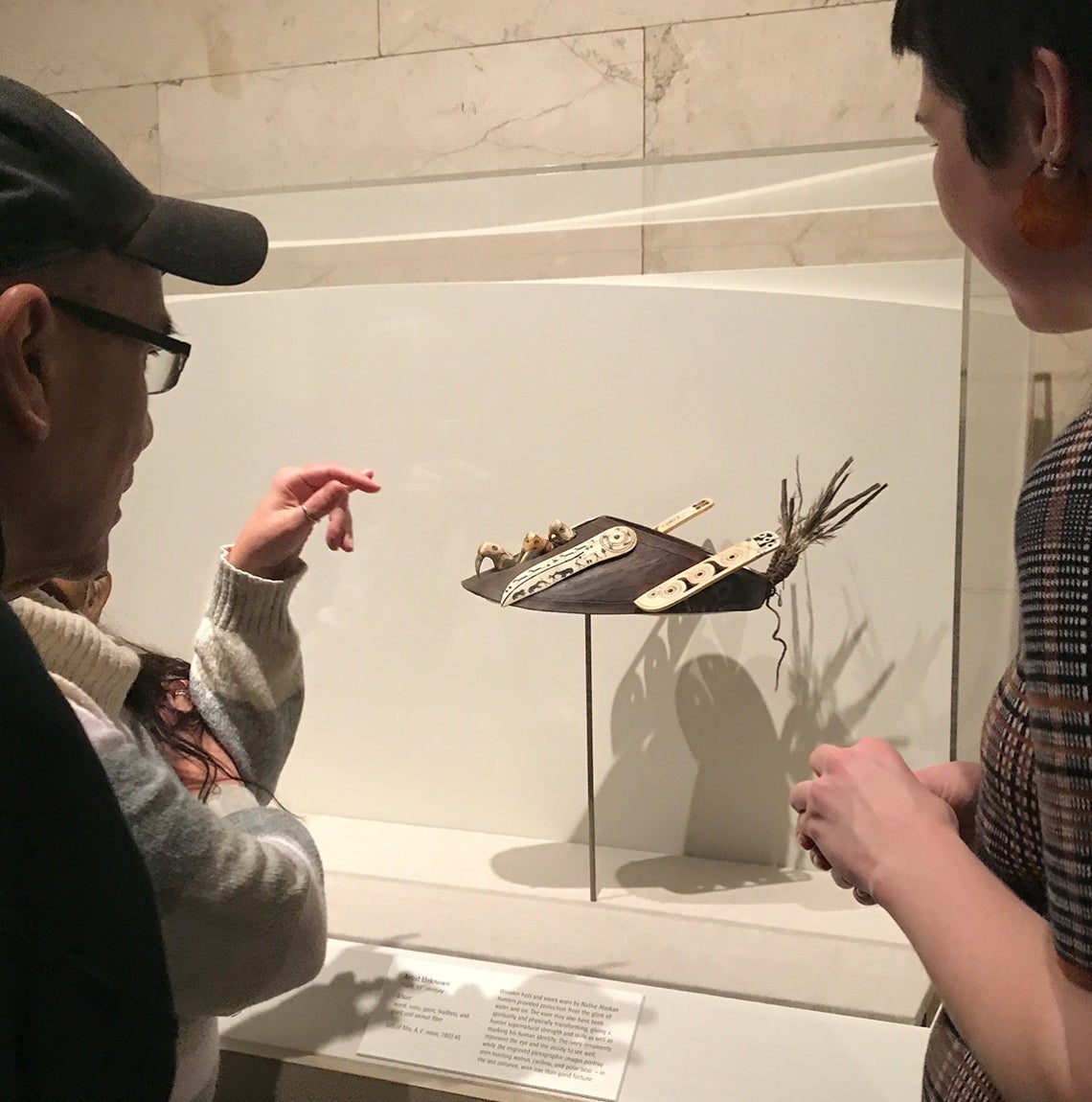 People view Native American visor as artifact in museum.