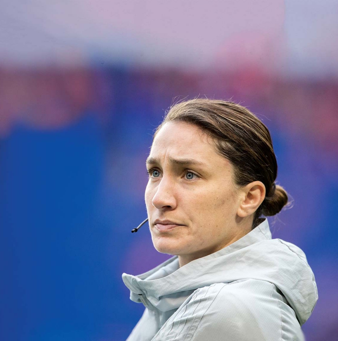 profile of woman with brown hair in bun at base of head, wearing slim headset with microphone