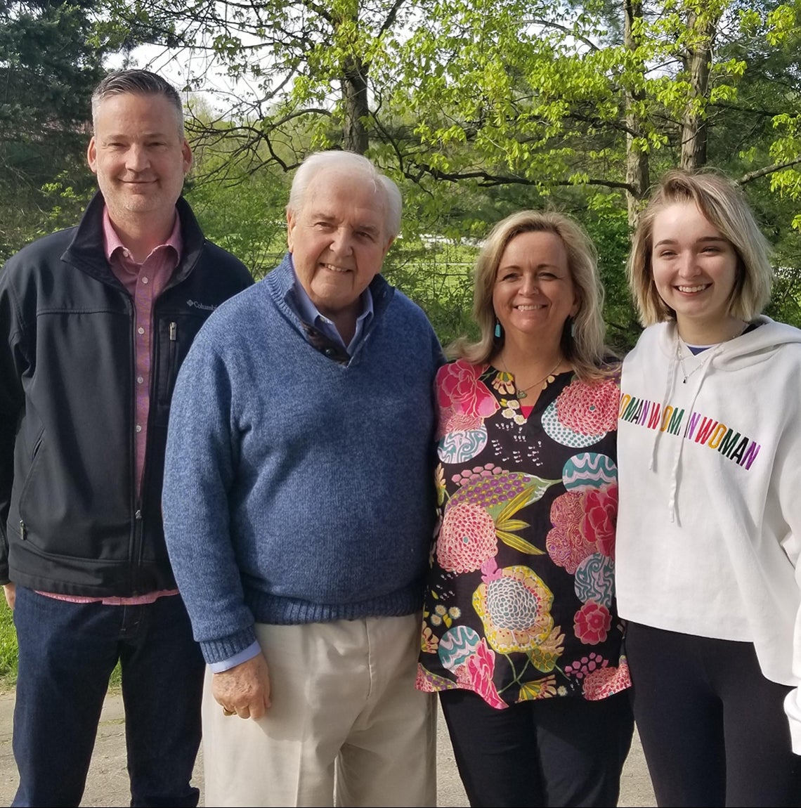 Todd Hiser, Zigmunt Walkiewicz Jr., Pam Hiser, and Megan Hiser stand in front of deciduous trees.