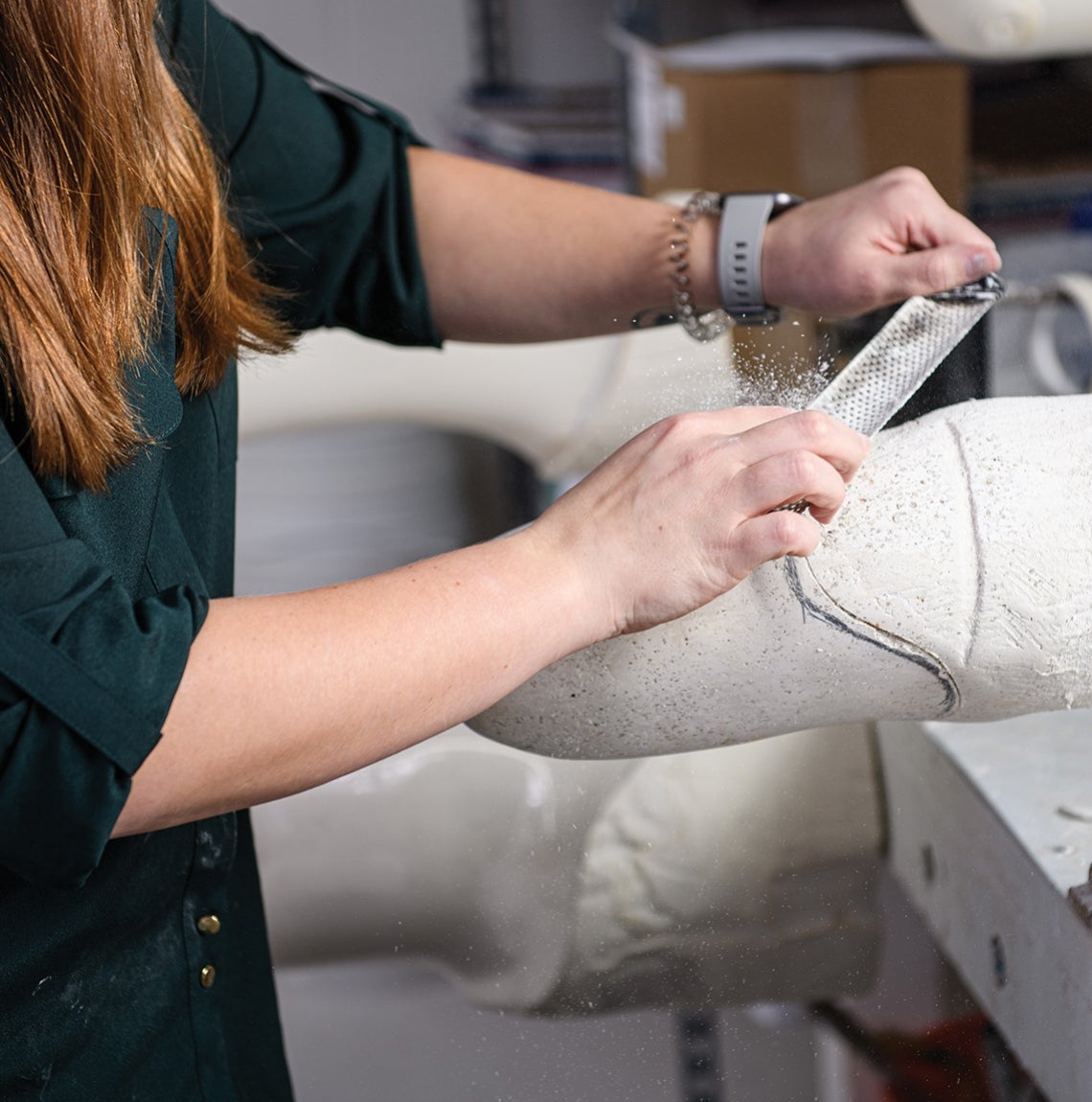 With the plaster cast of a patient’s residual limb held in place on her work bench, Caulfield files the surface smooth.